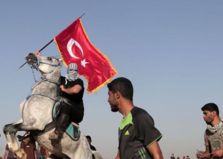 תצלום: מפגין בעזה, רוכב על סוס, מחזיק בדגל תורכי במהלך הפגנת "צעדת המיליון של ירושלים" ב- 8 ביוני 2018, לציון יום ה"נכסה" ויום אל-קודס (יום ירושלים) בגבול עזה-ישראל.